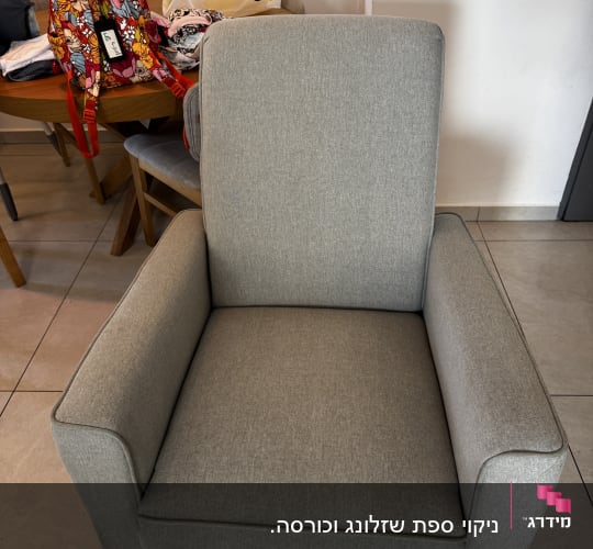 כורסה אפורה עם תיק צבעוני ברקע